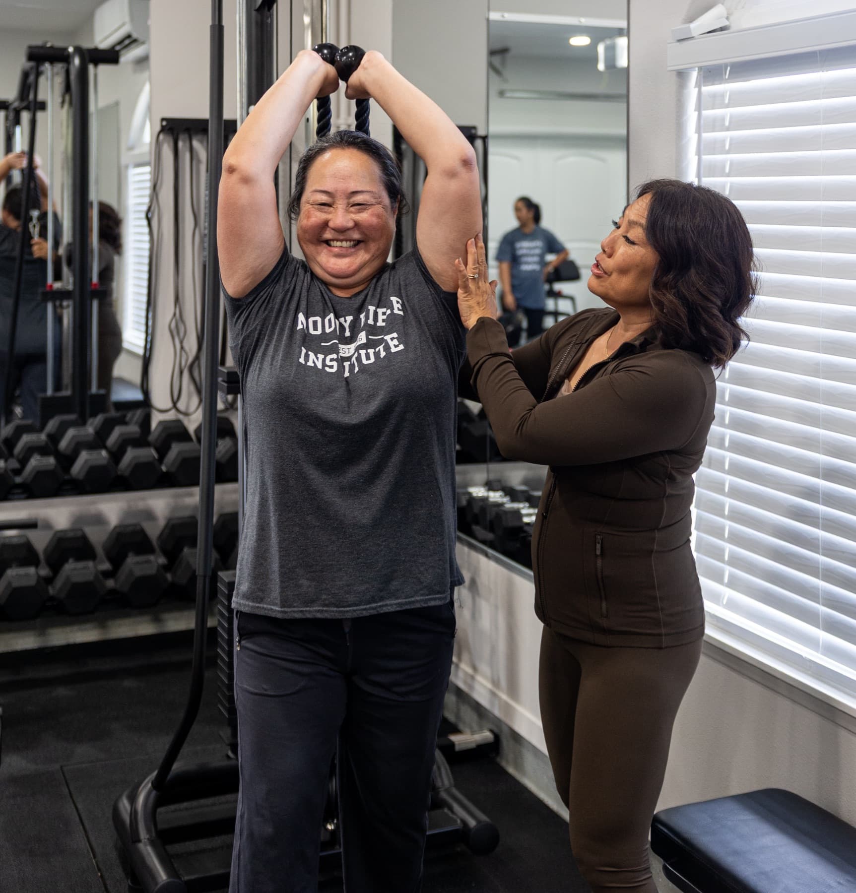 Lissa coaching a smiling member through a cable lift.