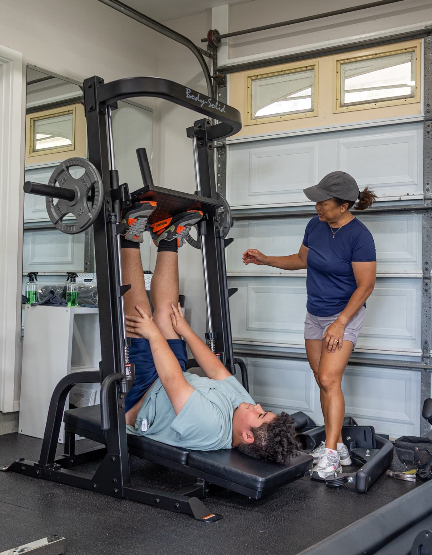 Lissa coaching a member through a leg press in her Hilo studio.